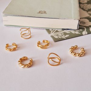 6 bagues d'oreilles dorées sur fond clair et vert pâle