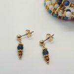 mini boucles d'oreilles avec pierres bleues apatite posées sur fond blanc